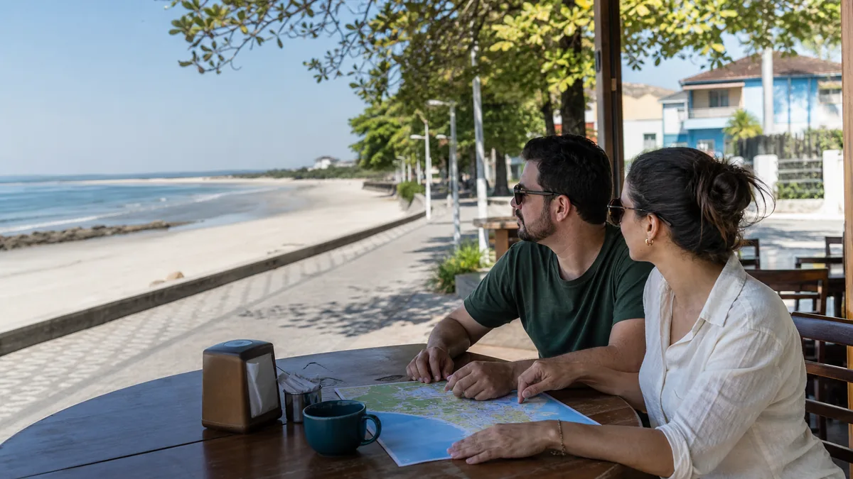 Casal organiza um roteiro de viagem diante da praia de Itapoá